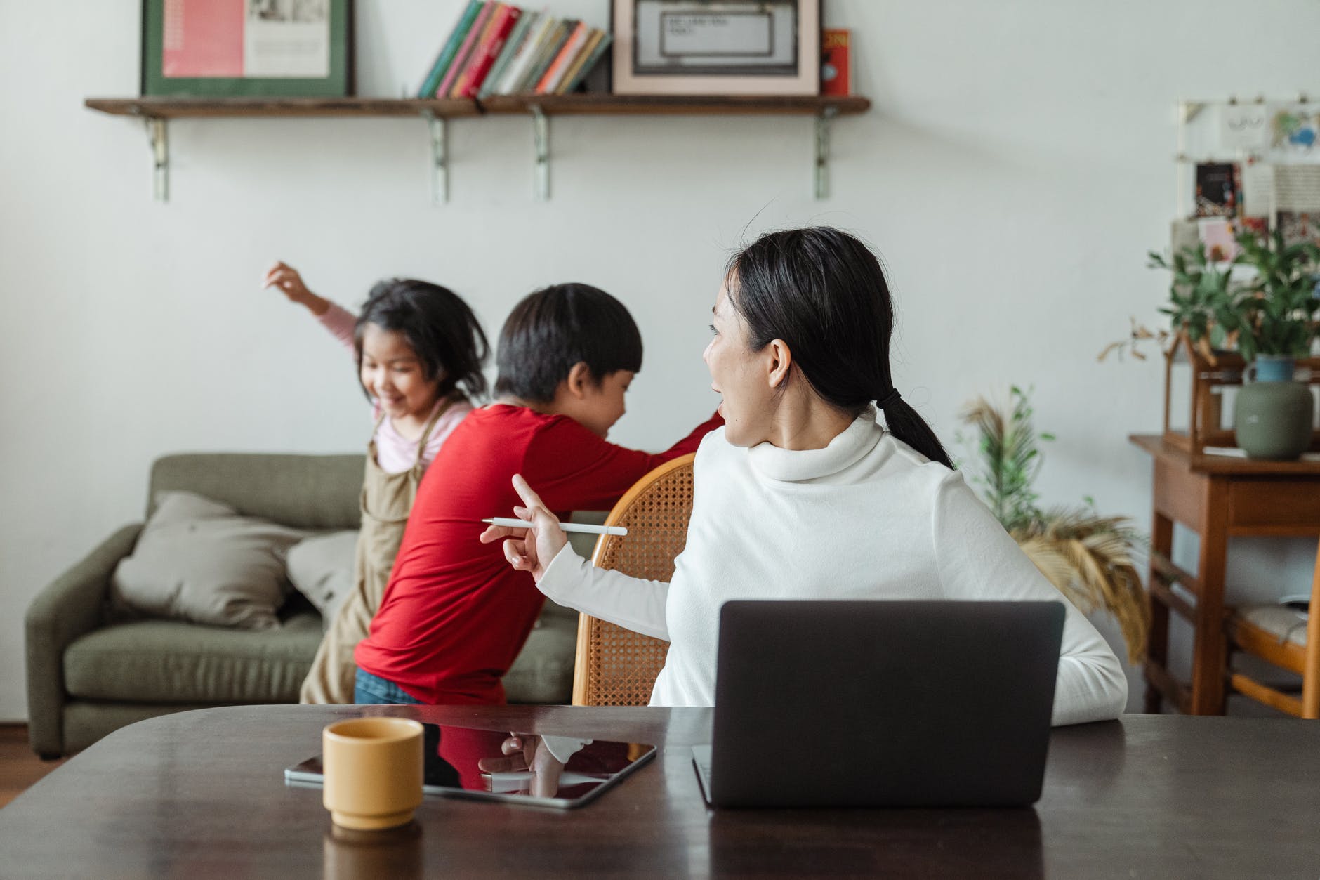 young ethnic woman trying to work at home with active children