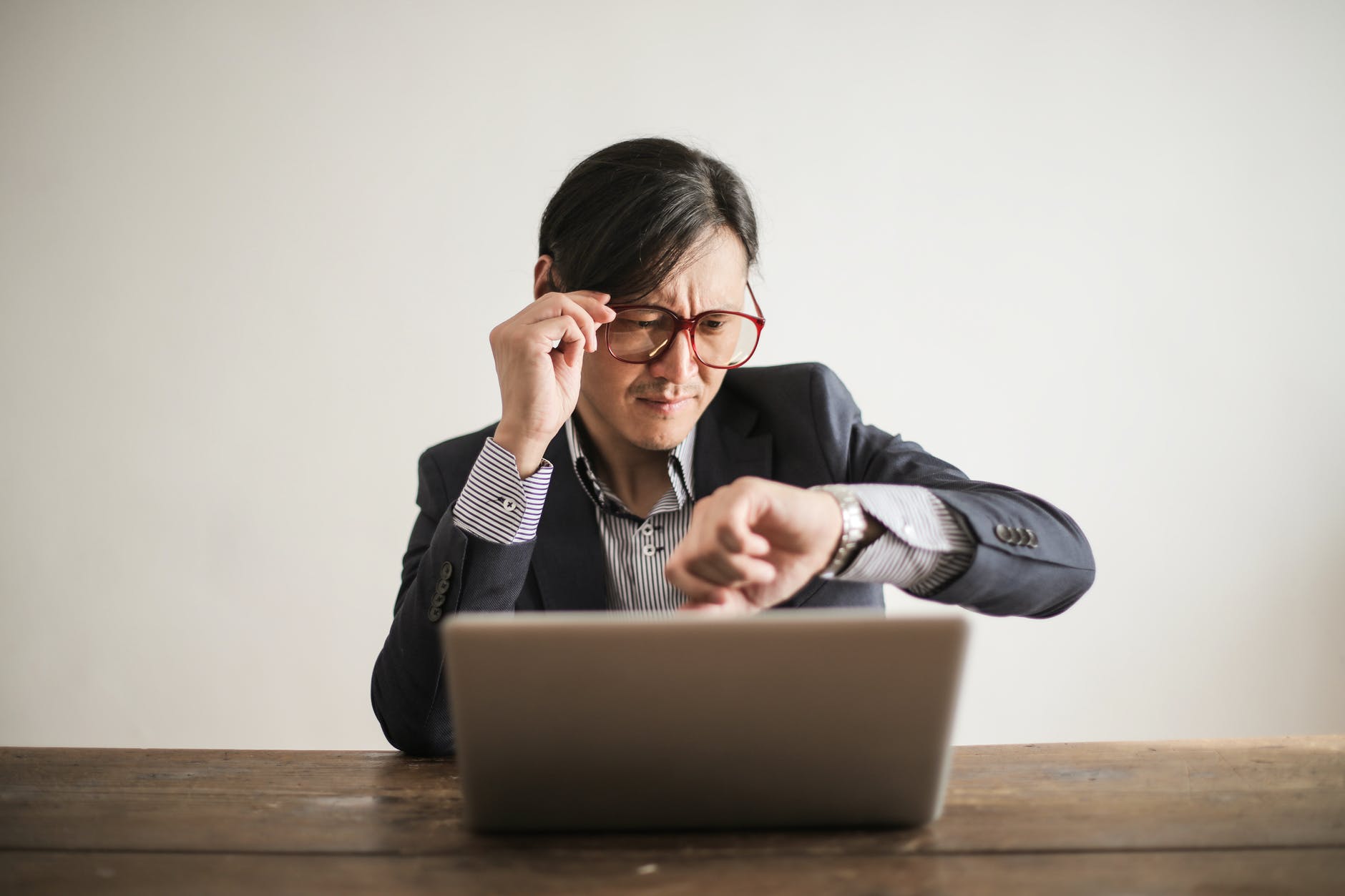 confused businessman checking time on wristwatch