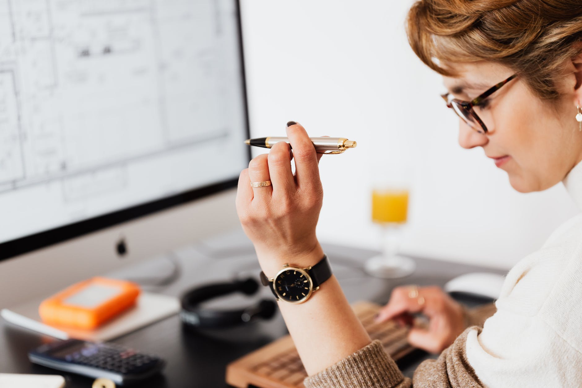 pen in hand of female typing on computer during work in office