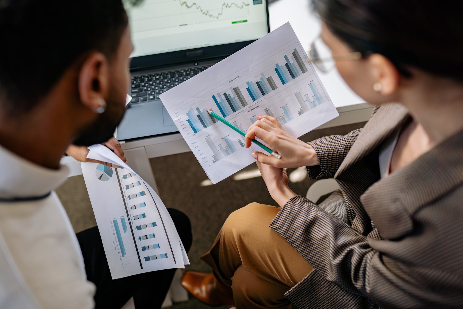 two people discussing graphs on printouts